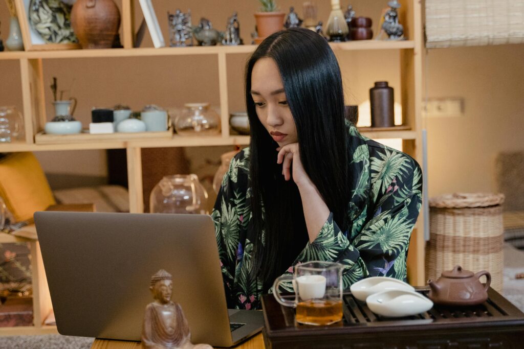 pexels photo 6545355 6545355 An Asian woman in a floral kimono focuses on her laptop while enjoying tea indoors.